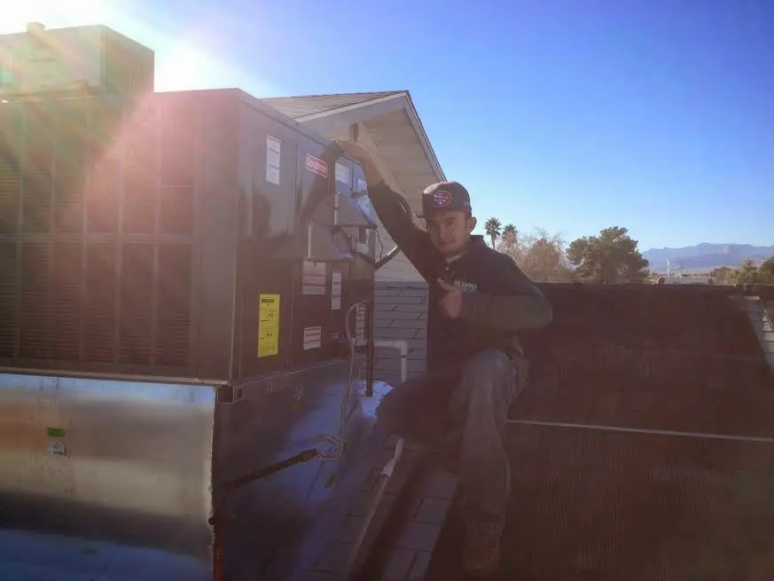 HVAC technician performing Air Duct Cleaning on a rooftop unit in Andalusia